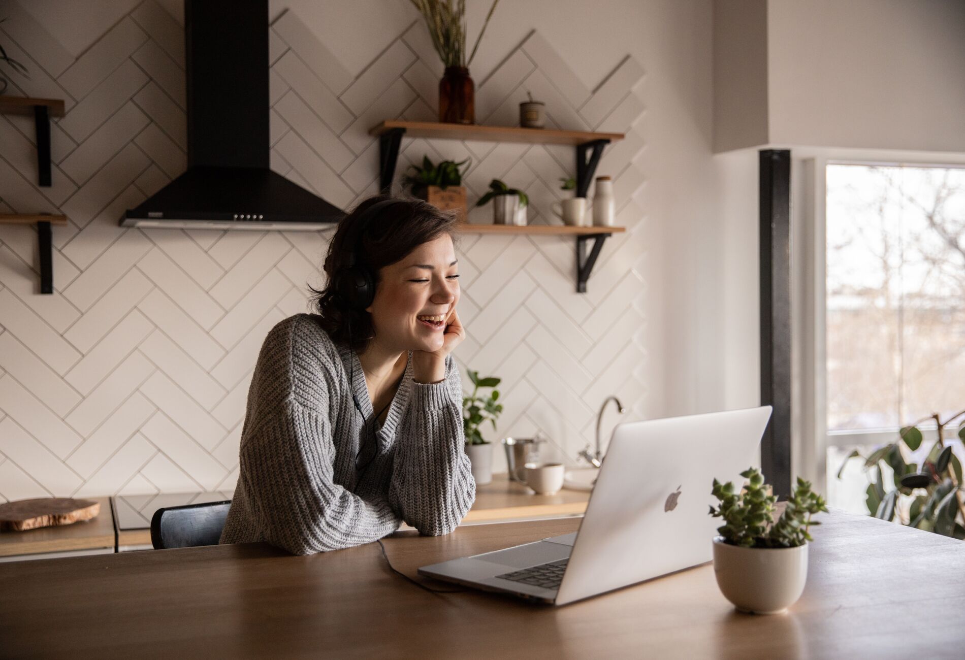 Vrouw met laptop aan de keukentafel